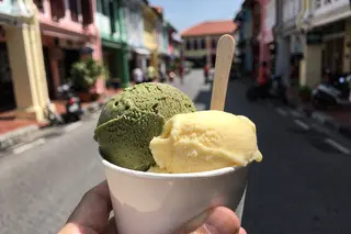AI illustration: Two scoops of pistachio and mango gelato in a cup on a sunny George Town street
