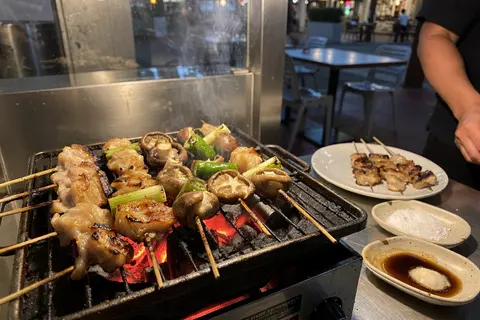 AI illustration: Yakitori skewers grilling over charcoal at a late-night izakaya counter