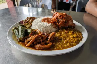 AI illustration: A plate of Ipoh nasi kandar topped with curry gravy, ayam merah fried chicken, okra and squid