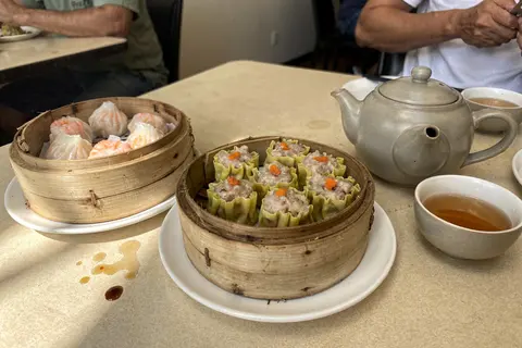 AI illustration: Bamboo baskets of har gow and siew mai with a teapot on a table during a Melaka yum cha breakfast