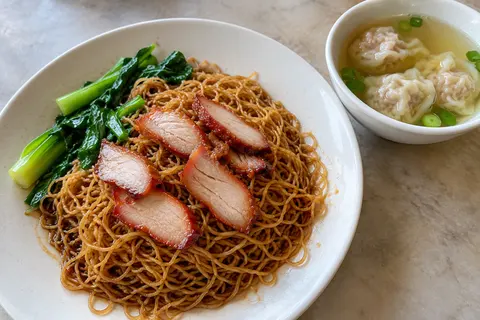 AI illustration: Dry wantan mee with fine egg noodles, thin char siu slices, leafy greens and a small bowl of wonton soup.